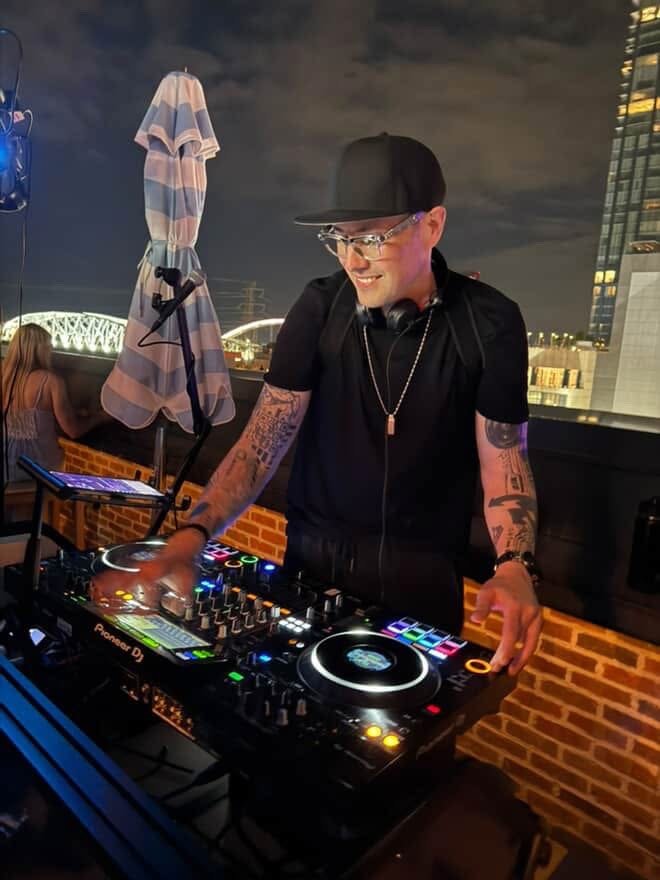 Aaron Traylor working behind a DJ controller at an outdoor venue.